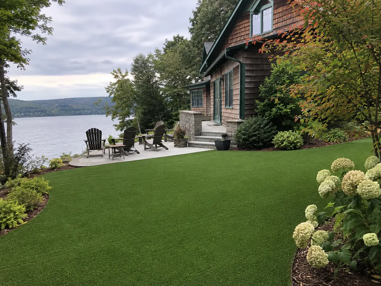 A vibrant and lush green artificial turf lawn installed in a modern backyard garden with stone pavers.