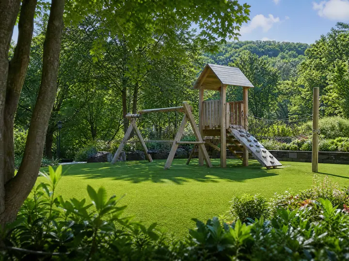 A vibrant green playground turf installation featuring colorful equipment and a soft, safe surface for children playing outdoors.