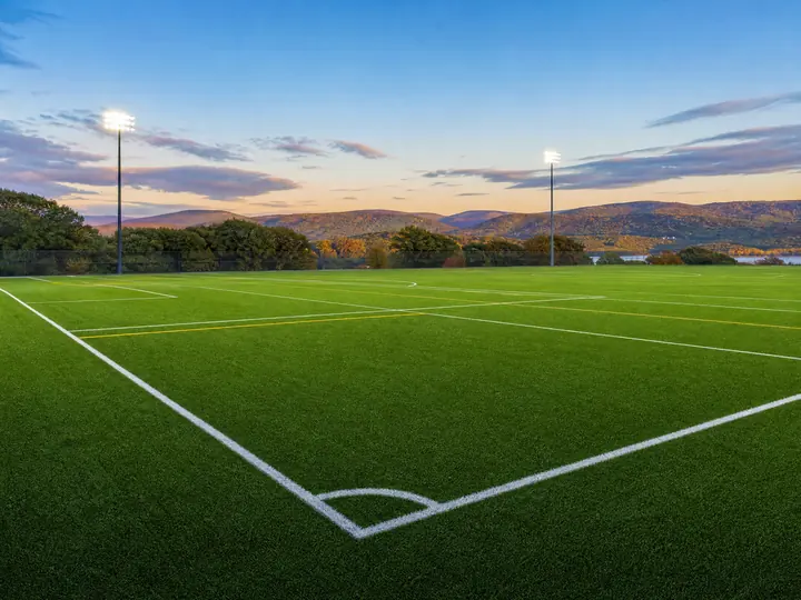A professional sports training turf field showing crisp white boundary lines and durable green synthetic grass blades.