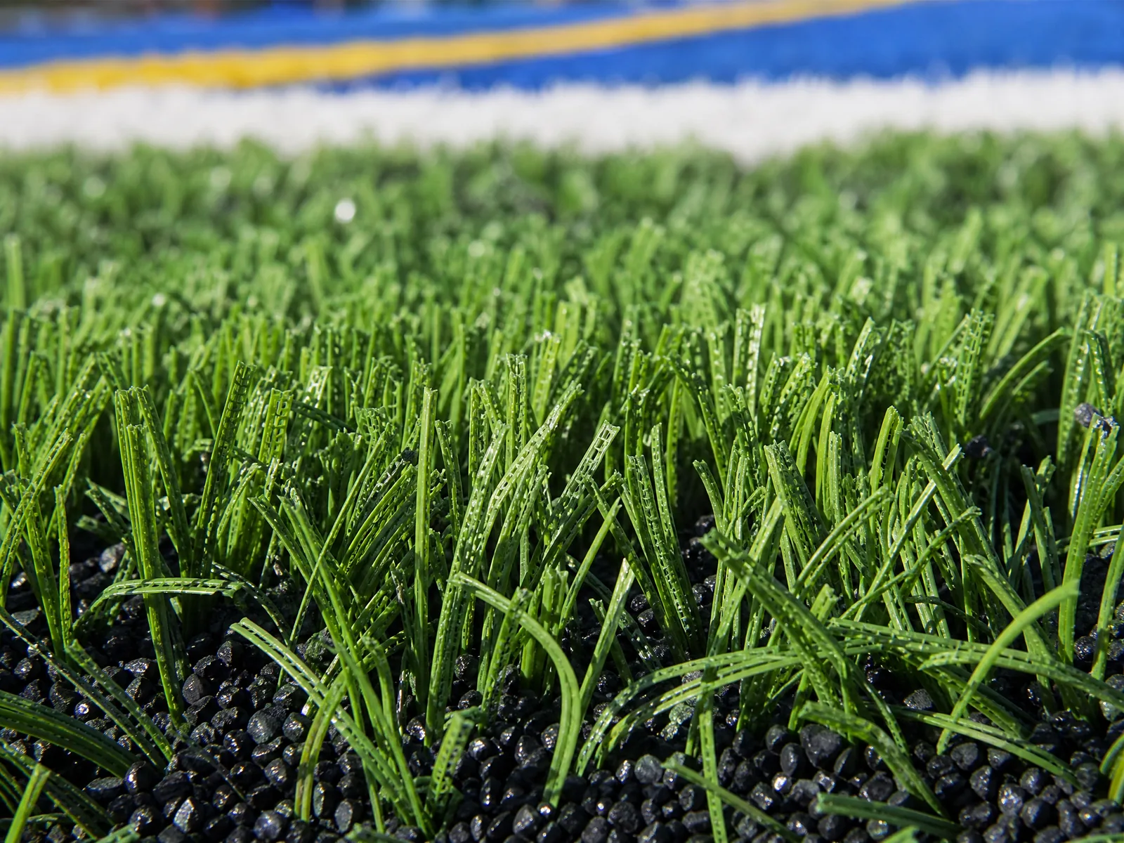 A professional indoor training facility featuring green fibrillated turf installed across a large multi-sport agility practice area.